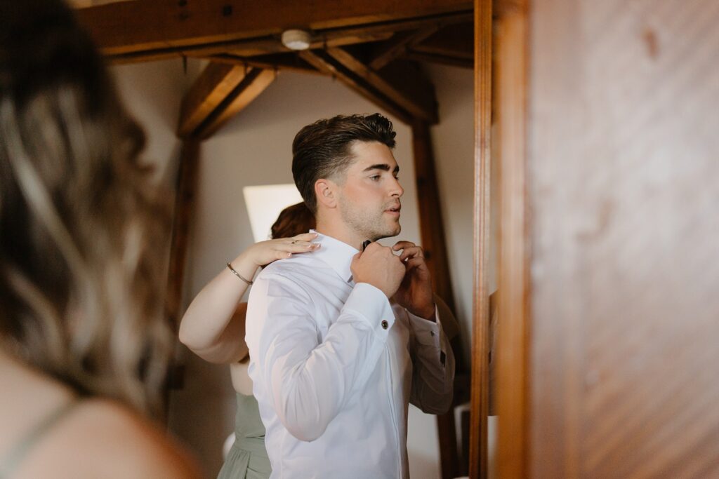 Habillage du marié dans une chambre du Domaine de la Fauconnie en Dordogne par la photographe de mariage Jade Sequeval