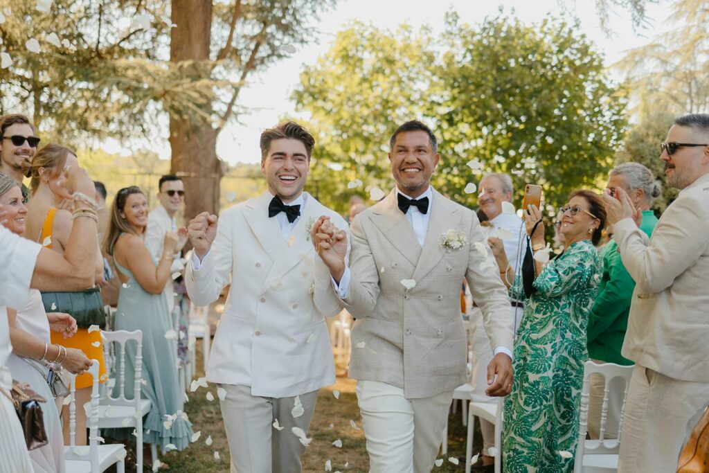 Sortie des mariés main dans la mains à la fin de leur cérémonie laique au Domaine de la Fauconnie en Dordogne par la photographe de mariage Jade Sequeval